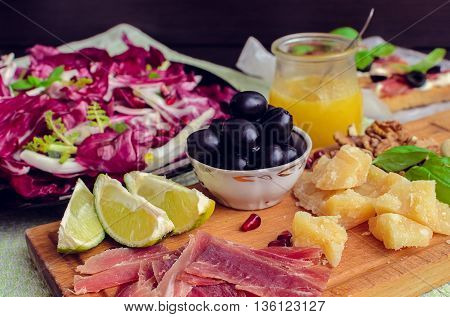 Sliced prosciutto with vegetable chicory salad cheese and olive. Appetizers set. Table full of mediterranean appetizers tapas or antipasto. Italian food. Selective focus.