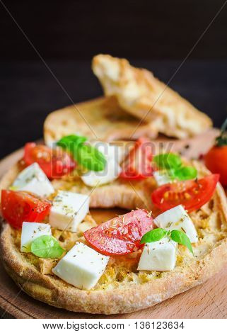 Italian appetizer Friselle. Italian dried bread Friselle on wooden board with tomatoes cherry basil and pepper. Italian food. Healthy vegetarian food. Antipasti concept. Selective focus.