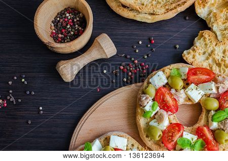 Italian appetizer Friselle. Italian dried bread Friselle with tomatoes cherry cheese mozzarella olives tuna basil and pepper in wooden pounder. Italian food. Healthy vegetarian food. Top view.