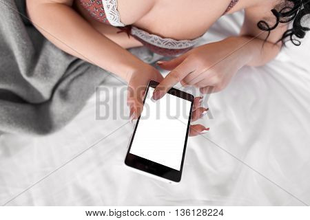 Naked woman using smartphone with white sceen. Top view on woman in bed using mobile phone with empty for advertisement screen