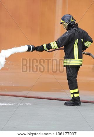 Fireman With An Extinguisher With Foam Under The Orange Smoke