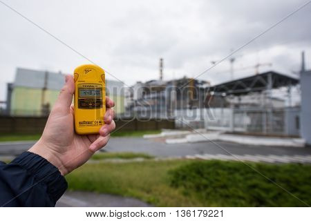 Pripyat, Ukraine - May 29, 2016: radiometer in hand with fourth Chernobyl reactor on the background