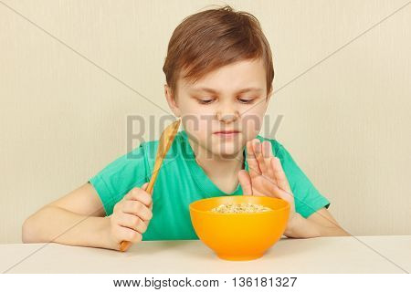 Little displeased boy refuses to eat a porridge