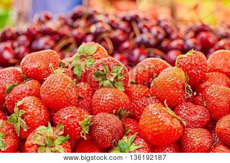 Сounter on the market: strawberry in the foreground and cherries in the background
