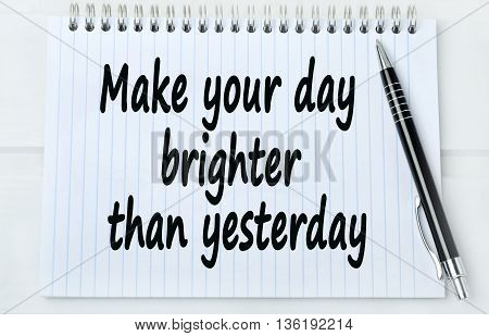 Text Make your day brighter than yesterday on notebook