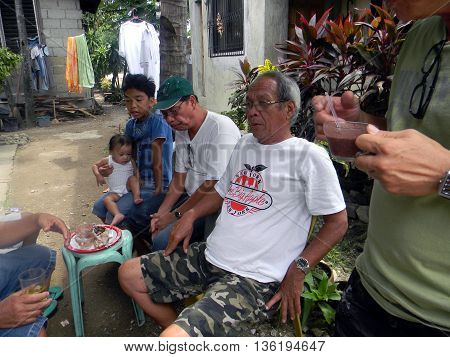 CEBU CITY, CEBU / PHILIPPINES - JULY 29, 2011: Men eat and drink together outside of a home in Cebu City.