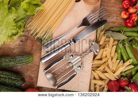 Italian food background, with vine tomatoes, basil, spaghetti, mushrooms, olives, parmesan, olive oil, garlic, peppercorns, rosemary, parsley and thyme. Slate background.