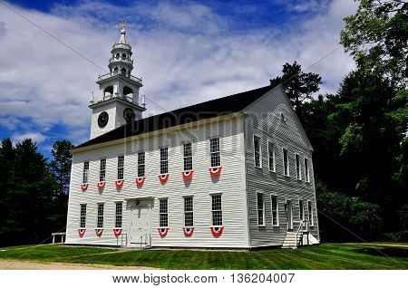 Jaffrey Center New Hampshire - July 11 2013: Red white and blue bunting decorates the windows at the 1775 Original Meeting House church with its steeple and bell tower