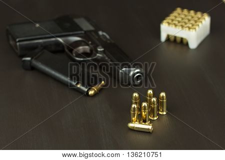 Handgun with ammunition on a dark wooden table. Sales of weapons and ammunition. Advertising on ammunition. New gun and ammunition. Grocery ammunition. The supply of ammunition for the defense.