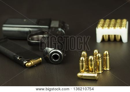 Handgun with ammunition on a dark wooden table. Sales of weapons and ammunition. Advertising on ammunition. New gun and ammunition. Grocery ammunition. The supply of ammunition for the defense.