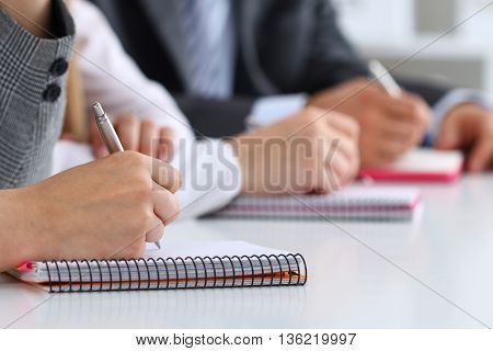 Close up view of students or businesspeople hands writing something during conference. Business meeting blogging or professional education concept