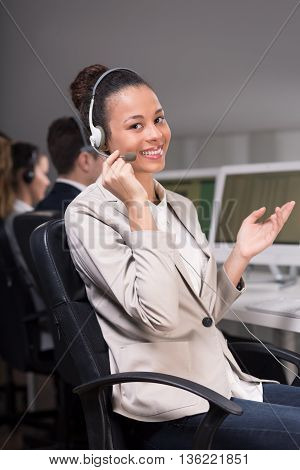 Young female consultant sitting on a chair and explaining something to the client by telephone