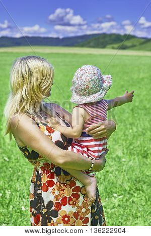 Standing young woman holding in their hands her child