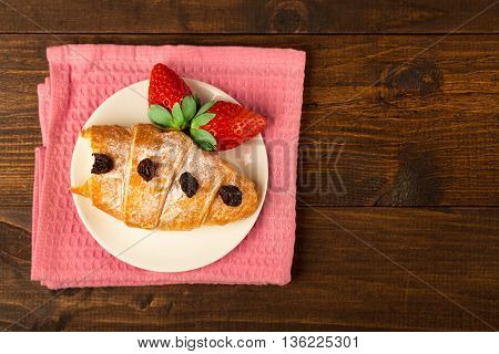 Delicious breakfast with fresh croissants and ripe berries on old wooden background selective focus top view