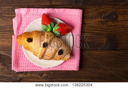 Delicious breakfast with fresh croissants and ripe berries on old wooden background selective focus top view
