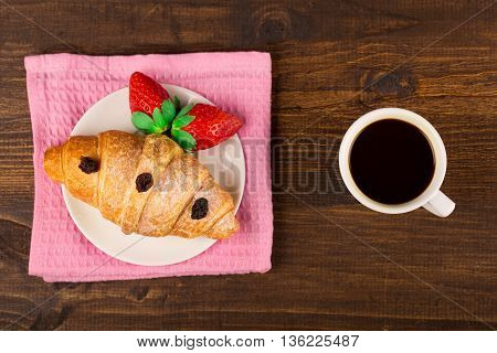 delicious golden croissants filled with strawberry marmalade and coffee. wooden table background. Top view