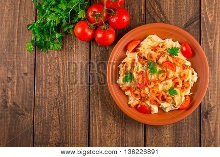 Fettuccine pasta with shrimp tomatoes and herbs. wooden background. Top view