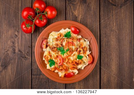 Fettuccine pasta with shrimp tomatoes and herbs. wooden background. Top view