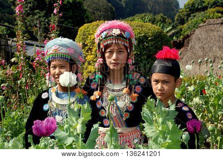 Doi Pui Thailand - December 24 2006: Thai family wearing vintage hilltop tribal village clothing in a garden of opium poppies