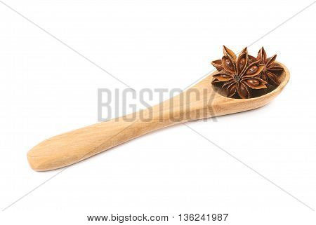 Chinese star anise seed served in a wooden spoon, composition isolated over the white background