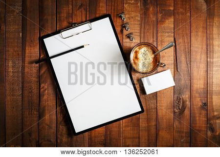 Blank paperwork template for designers. Responsive design mockup on vintage wooden background. Blank paper letterhead coffee cup business cards and pencil on wooden table background. Top view.