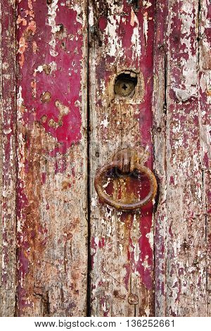 Old grungy wooden door with peeling paint and rough door-handle