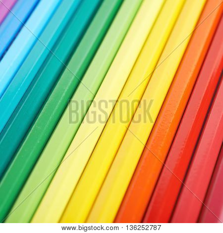 Multiple colorful color pencils composition arranged in a line to form a rainbow gradient, close-up crop fragment