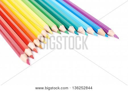 Multiple colorful color pencils composition arranged in a line to form a rainbow gradient, composition isolated over the white background