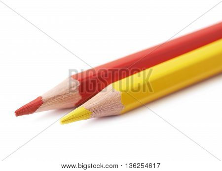 Two red and yellow colored drawing pencils composition isolated over the white background, close-up crop fragment