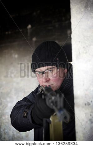machine gunner in black uniforms and protective glasses aim of the shelter