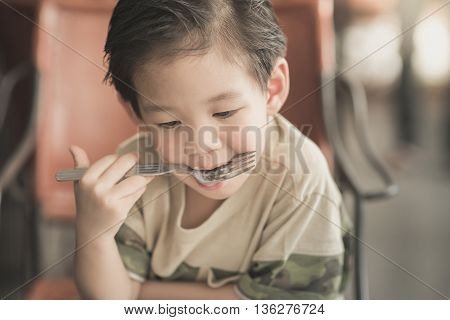 Cute Asian chid eating Spaghetti Carbonara in restaurant vintage fiter