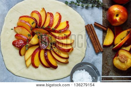 Baking a fruit pie with peaches nectarines. The ingredients on the table - dough peaches nectarines sugar cinnamon thyme. Selective focus