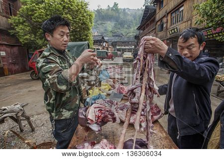 Zhaoxing Dong Village Guizhou Province China - April 8 2010: Asiatic buying pig entrails from a street vendor in the Chinese countryside.