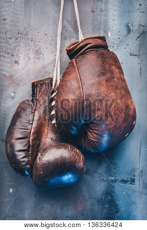 pair of brown vintage boxing gloves hanging on a metal wall