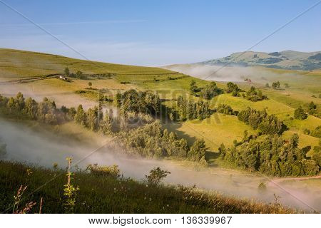 Colorful morning mist up the hills in the Romanian Apuseni Mountains near Salciua