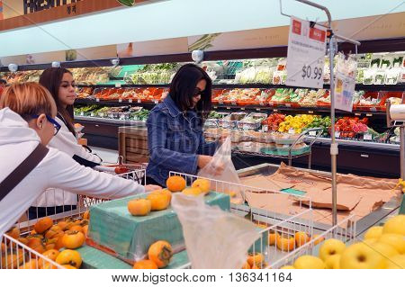 NAPERVILLE, ILLINOIS / UNITED STATES - NOVEMBER 3, 2015: People shop for fresh persimmons at the Super H Mart Korean supermarket in Naperville.