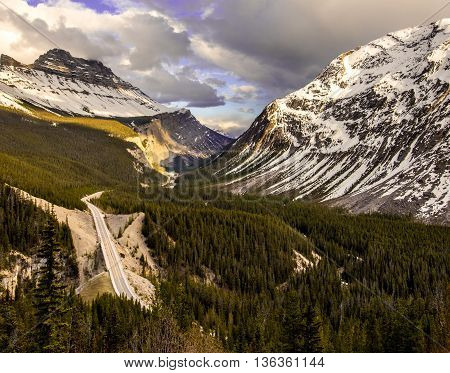 Car drives on a road through a valley in the rocky mountains.