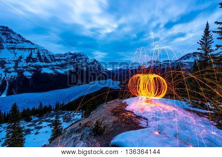 circle of burning steel wool in the winter above frozen peyto lake.
