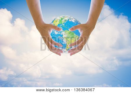 Human hands on both sides holding the world sky in the background blurred.Environment Day concept. Ecology concept.Environment Day concept. Ecology concept..Elements of this image furnished by NASA.