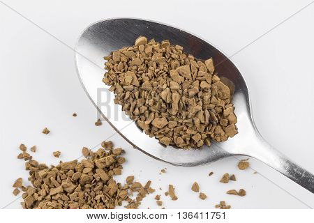 Close focus on premium brown decaf coffee power putting on stainless steel teaspoon and white background