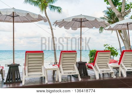 Beautiful beach chairs with umbrella around outdoor swimming pool neary sand and sea