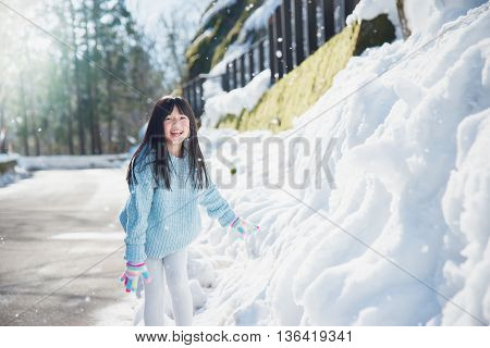 Happy asian girl smiling outdoors in snow on cold winter day