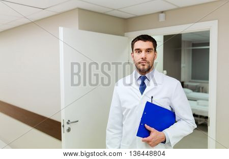 medicine, healthcare and people concept - doctor with clipboard at hospital