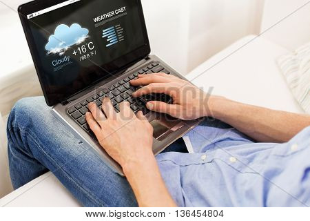 technology, weather cast, people and lifestyle concept - close up of male hands typing on laptop computer with meteo forecast on screen at home