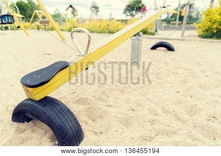 childhood, equipment and object concept - close up of swing or teeterboard on playground outdoors