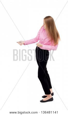 back view of standing business woman pulling a rope from the top or cling to something.  Isolated over white background. The girl office worker in black slacks standing sideways pulls on the rope.