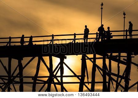 Silluate man on wooden bridge during at sunset in Kanjanaburi Thailand