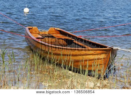 Wooden rowboat in warm evening light in the reed straw