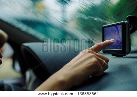 woman looking road on the map GPS Navigator sitting behind the wheel of a car on a rainy day