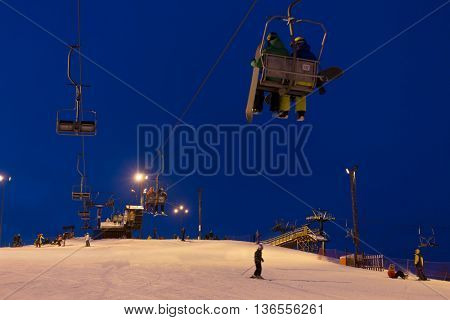 Cableway above snowy slope at ski resort in evening time.